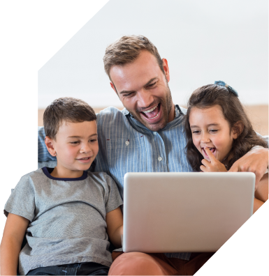 A happy father and two children laugh together at something on a computer screen