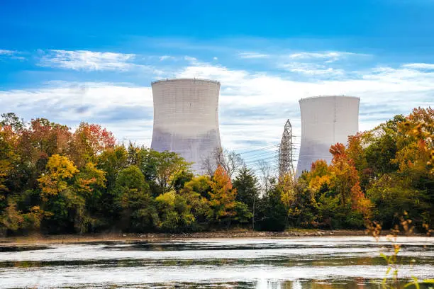 Two large cement nuclear towers rising above autumn forests
